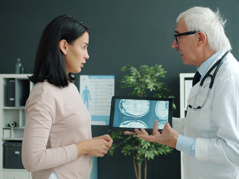 Arzt zeigt einer Patientin Aufnahmen auf dem Tablet